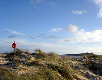 Embleton beach with life belt and Dunstanburgh Castle in the distance
